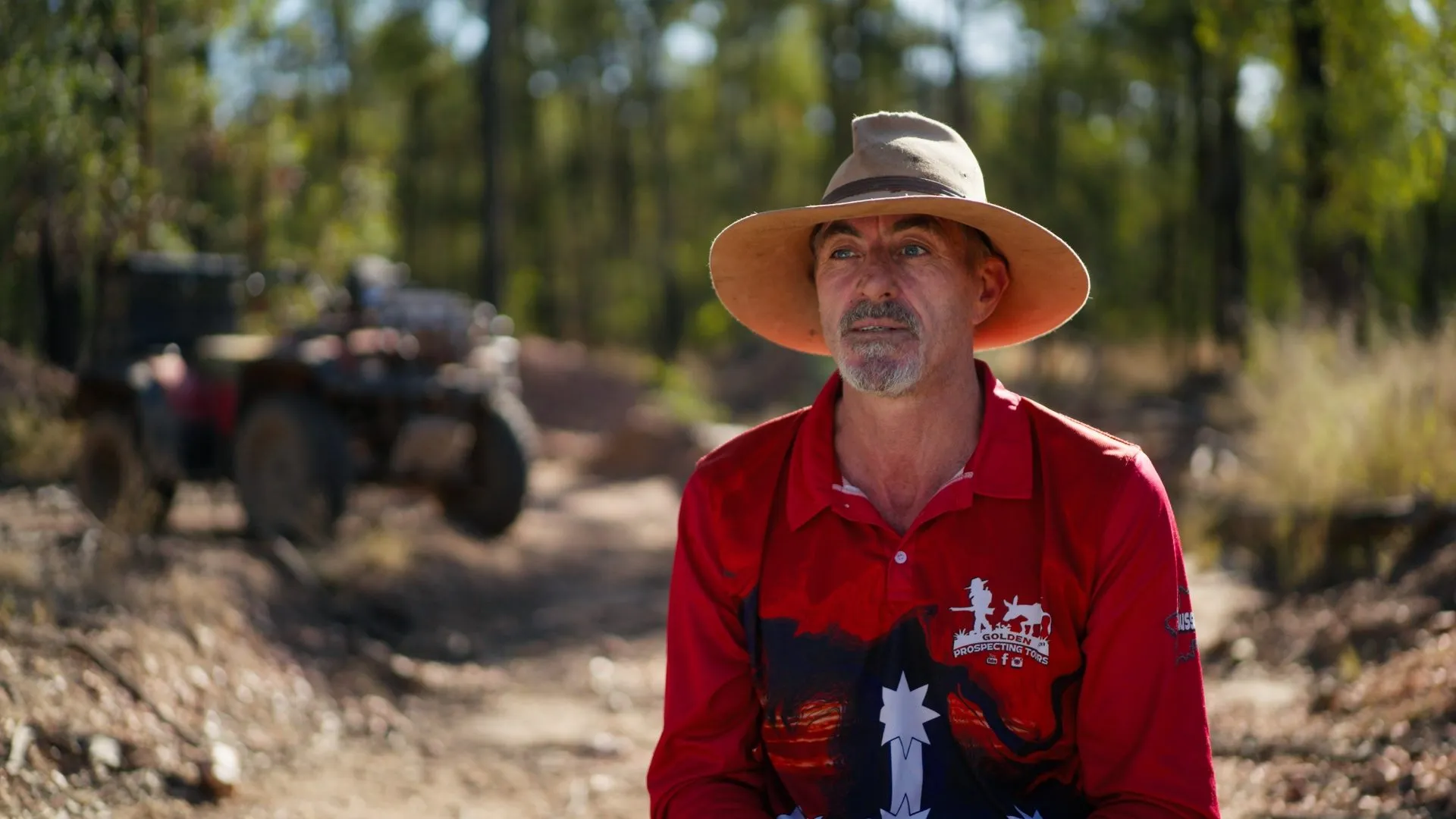 A prospector in a wide-brimmed hat in the bush