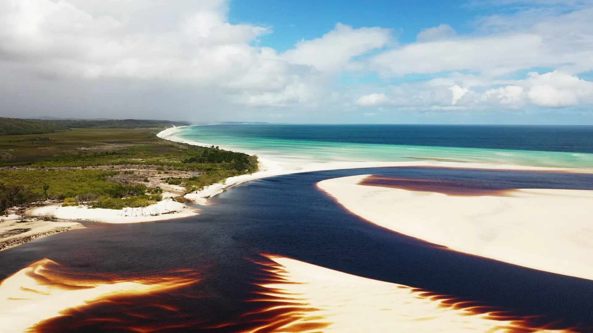Aerial view of a river meeting a white sand beach