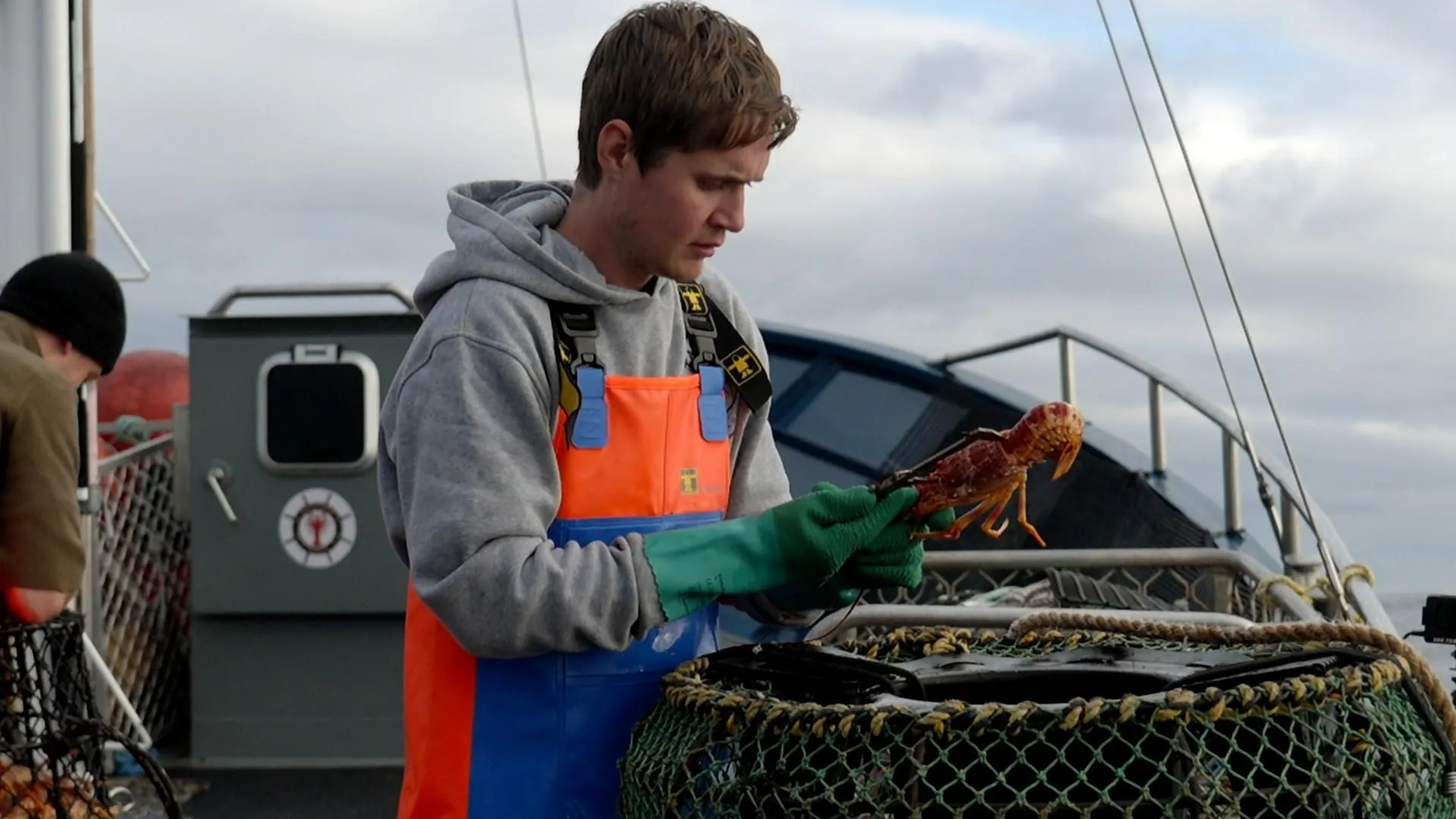 A deckhand sorting a lobster catch on a fishing boat